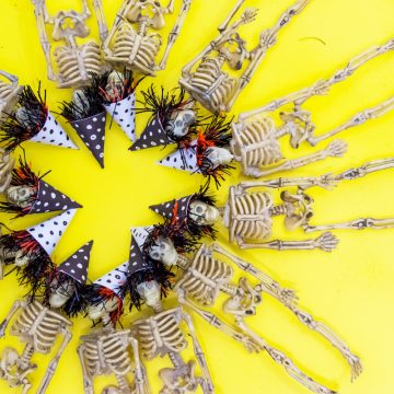 Make your dollar store purchases go even further with thiseasy halloween skeleton garland. They're ready for the party with their adorable mini party hats. #halloween #hotglue #cricutmade